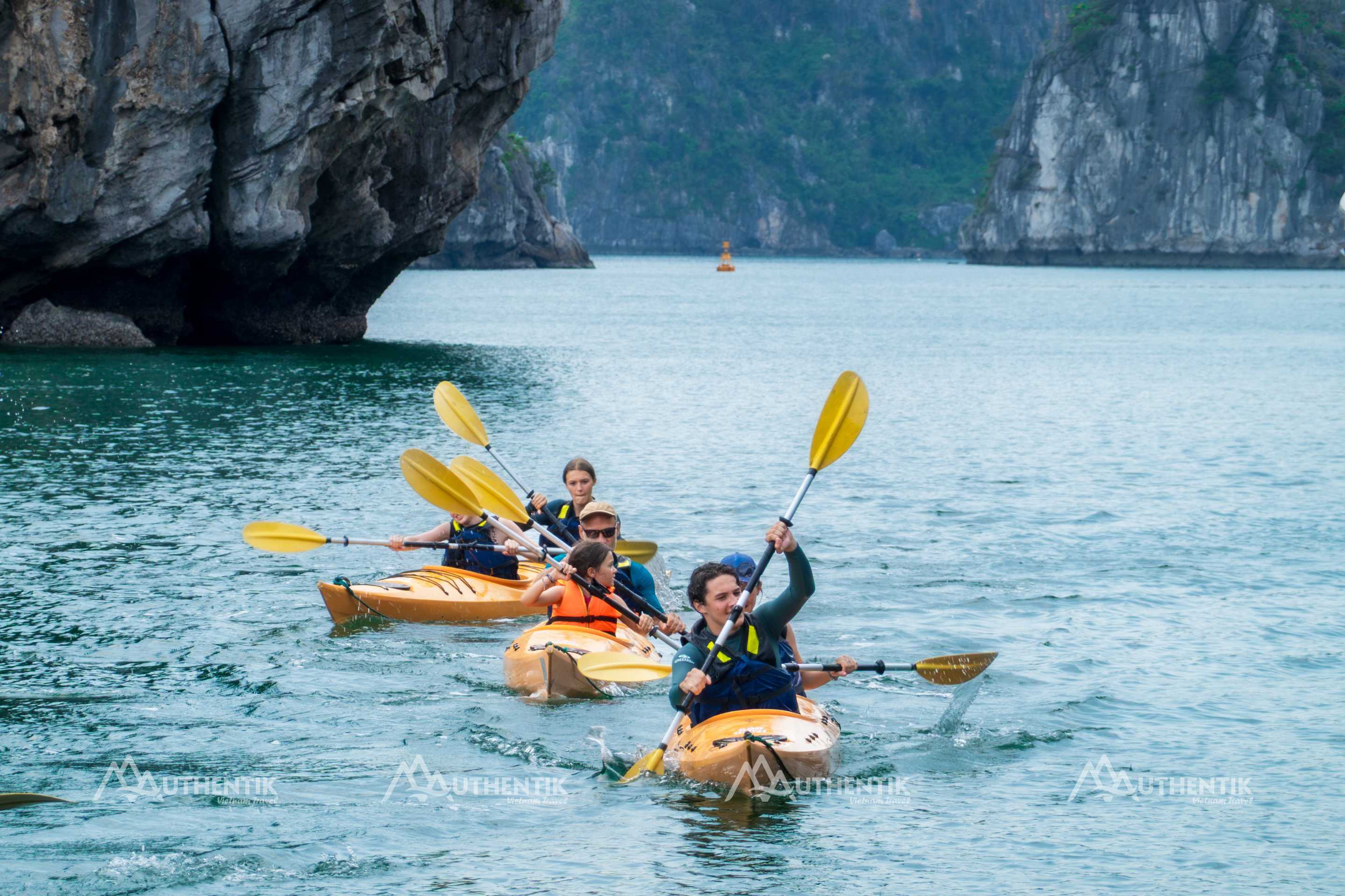 Travelers kayaking in the calm waters of Bai Tu Long Bay
